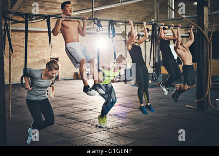 Junge Menschen tun Pullups suchen entschlossen, trainieren Sie im Fitnessraum fit Stockfoto