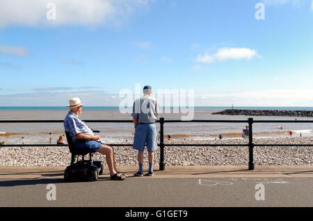 Ältere Herren, einer in einer Mobilität scooter mit Blick auf das Meer im Sommer am Meer Sidmouth Stockfoto