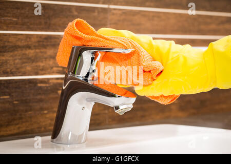 Frau tun Hausarbeiten im Badezimmer, moderne Wasserhahn reinigen. Stockfoto