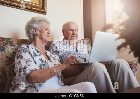 Älteres Ehepaar mit Laptop-Computer zu Hause. Ältere Mann und Frau auf Sofa arbeiten am Laptop sitzt. Stockfoto