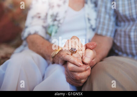 Beschnitten, Schuss älteres Ehepaar Hand in Hand beim Sitzen zu Hause zusammen. Konzentrieren Sie sich auf Händen. Stockfoto