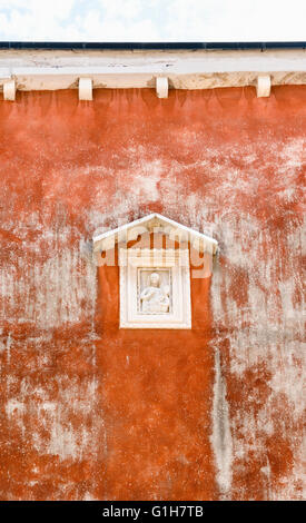 Kleines Wandrelief Schrein in einem Ocker bemalten Wand in Venedig, Italien Stockfoto
