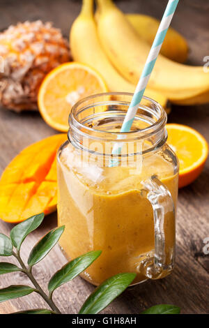 Smoothie mit tropischen Früchten: Mango, Banane, Ananas, Orange im Weckglas Mason auf dem alten hölzernen Hintergrund Stockfoto