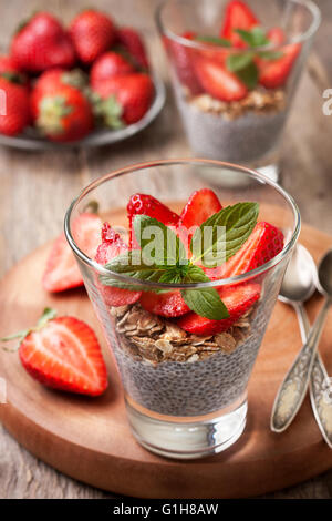 Ernährung, gesundes Frühstück. Chia Pudding, Erdbeeren und Müsli in einem Glas frischen Erdbeere auf einem alten hölzernen Hintergrund Stockfoto