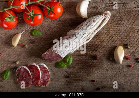 Italienische Salami mit Gewürzen und Gemüse über rustikale Holz Hintergrund Stockfoto