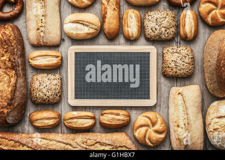 Frisches knuspriges Brot auf eine hölzerne Arbeitsplatte und leere Tafel, Bäckerei und gesunde Ernährung Konzept, flach legen banner Stockfoto