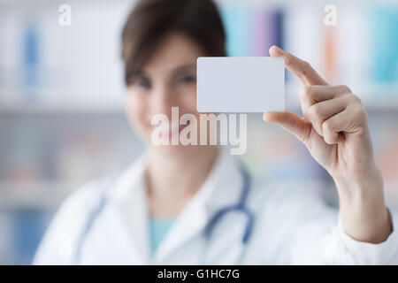 Lächelnd Ärztin hält eine leere Visitenkarte, Healthcare und Business-Konzept Stockfoto