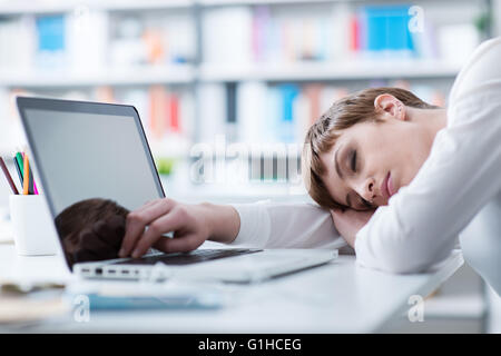 Schlafen auf ihrem Schreibtisch und stützte sich auf ihren Arm müde Geschäftsfrau Stockfoto