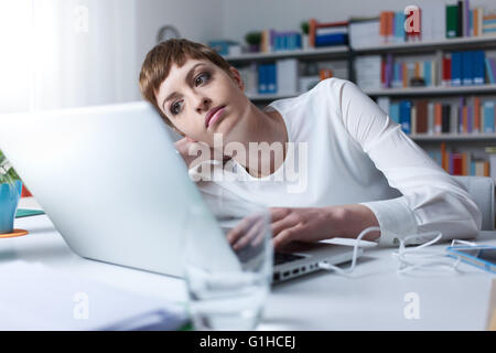Müde Frau im Büro stützte sich auf ihre Hand ein mit einem laptop Stockfoto