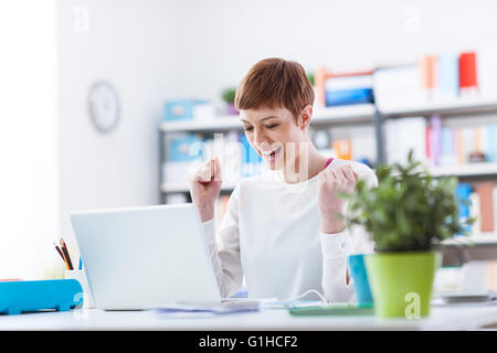 Fröhliche erfolgreiche Frau, die gute Nachricht auf ihrem Laptop, Gewinn und Erfolg Konzept Stockfoto