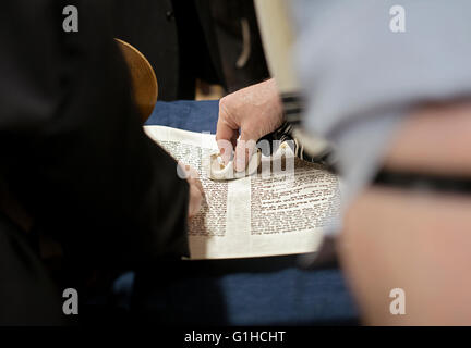 Ein religiösen jüdischer Mann berührt ein Ort, wo eine Tora-Lesung startet, wenn er für ein Segen bezeichnet wird. Brooklyn, New York. Stockfoto