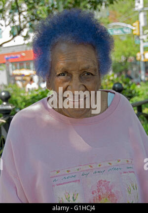 Porträt einer afrikanischen Frau in ihrer Mitte der 60er Jahre mit blauen Haaren. Im Union Square Park in Manhattan, New York City. Stockfoto