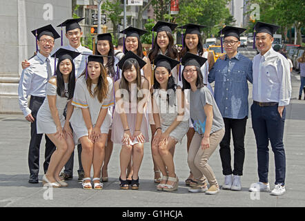Asiatische NYU Absolventen tragen ihre Abschluss-Kappen-Pose für ein Gruppenfoto im Washington Square Park in New York City Stockfoto
