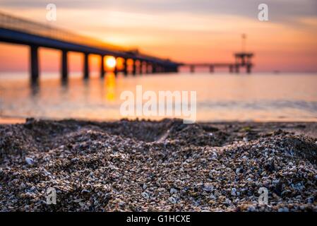 Sand am Strand. Unscharfen Hintergrund der Brücke und Sonnenaufgang. Stockfoto