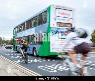 Radfahren im Straßenverkehr. Ein Bus vorbei an zwei Radfahrer auf einer geschäftigen Stadt Road, Nottingham, England, Großbritannien Stockfoto