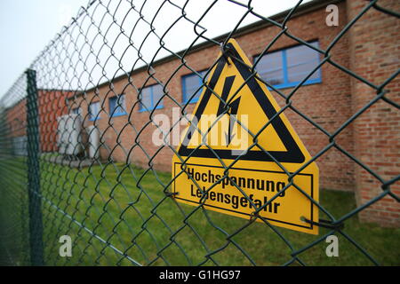 Hochspannungs-Zeichen auf einem Zaun in Deutschland. Die unteren Linien bedeuten Hochspannung Lebensgefahr. Stockfoto