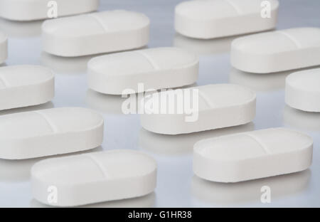 Reihen von weißen, Schmerzlinderung Tabletten auf eine glänzende Metalloberfläche in einem pharmazeutischen Fertigung Bild. Stockfoto