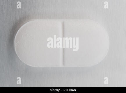 Eine einzelne weiße schmerzstillende Tabletten wie Paracetamol zeigt seine zwei Hälften für Kopie Speicherplatz auf einem silbernen Hintergrund. Stockfoto