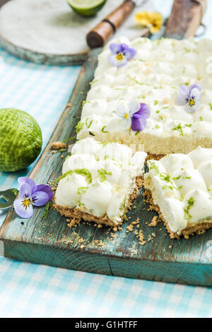 Vorgeschmack auf den Sommer, Key Lime Pie mit Blumen, in Scheiben geschnitten und serviert auf Holzbrett Stockfoto