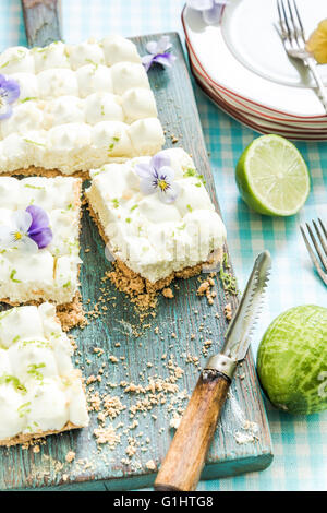 Vorgeschmack auf den Sommer, Key Lime Pie mit Blumen, in Scheiben geschnitten und serviert auf Holzbrett Stockfoto