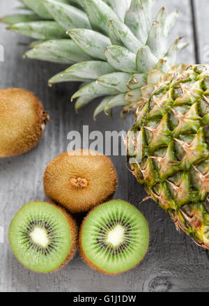 Leckere und gesunde Kiwi und Ananas Frucht auf grauem Hintergrund aus Holz Stockfoto