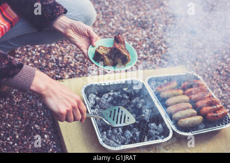 Eine junge Frau ist das Fleisch auf dem Grill kochen Stockfoto