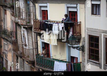 Portugal, Stadt Porto, Frauen hängen Wäsche zum Trocknen auf Haus Balkon, täglichen Routinetätigkeit Stockfoto