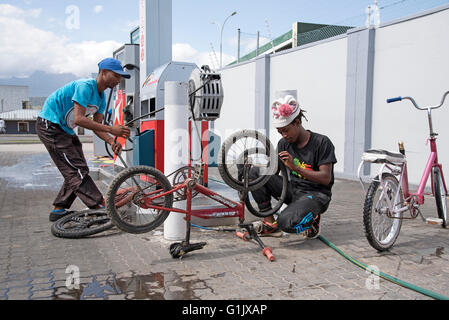 Junge afrikanische Männer, die Reparatur von Reifenpannen, Fahrradreifen an einer Tankstelle in Südafrika Stockfoto