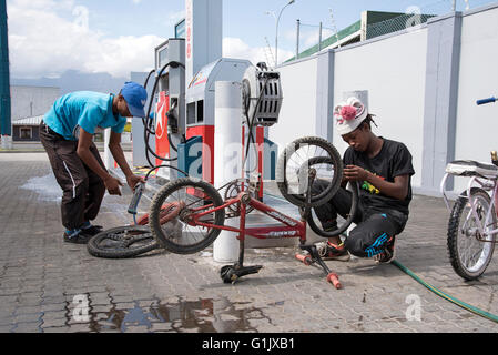 Junge afrikanische Männer, die Reparatur von Reifenpannen, Fahrradreifen an einer Tankstelle in Südafrika Stockfoto