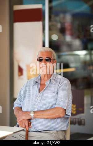 Älterer Mann an einem Tisch vor einem Geschäft wartet Stockfoto