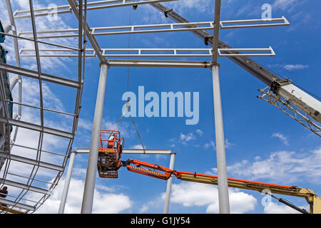 Höhe Arbeitskraft ist zu der mobile Kran helfen, um Teil zu platzieren, auf den Aufbau von Skelett. Stockfoto