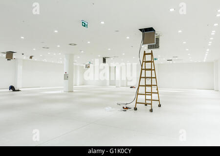 Arbeitnehmer dienen Holzleiter, komplette Klimaanlage System Ventilation im modernen Office-Decke mit Luftkanal und Lampen. Stockfoto