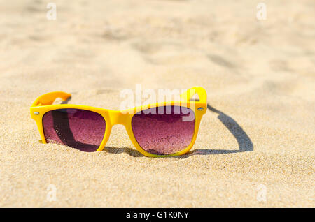 Gelbe Sonnenbrille in den Sand am Strand Closeup. Stockfoto