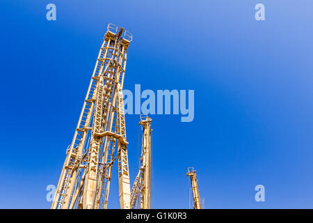 Türme von Bohrmaschinen stehen hoch hoch am blauen Himmel im Hintergrund. Stockfoto