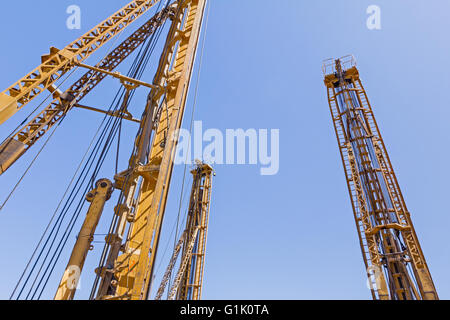 Türme von Bohrmaschinen stehen hoch hoch am blauen Himmel im Hintergrund. Stockfoto