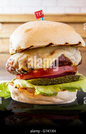 Großer Burger mit Käse, Salat, Tomate, Zwiebel und Gurke Stockfoto