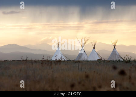 Tipis bei Sonnenuntergang auf den Ebenen von Colorado unter einem Gewitter vorbeigehen. Stockfoto