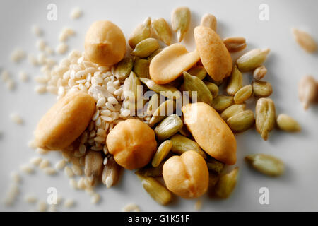 Gesunde Mischung aus Erdnüsse, Haselnüsse, Sonnenblumenkerne & Sesam vor einem weißen Hintergrund, Top Shot Stockfoto