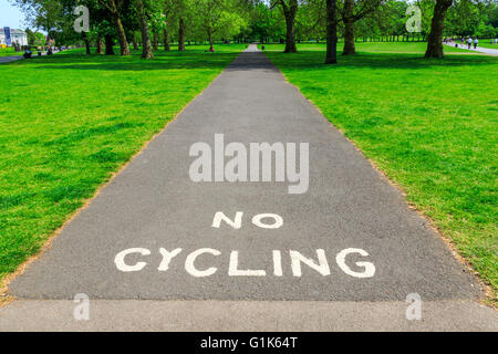 "Kein Radfahren" Warnung geschrieben mit weißer Farbe auf Asphalt Asphalt sichtbar Baum und Gras im Hintergrund Stockfoto