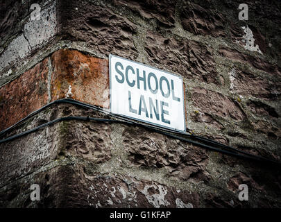 Ein Schild mit Schule Lane an der Seite eines Gebäudes im Vereinigten Königreich Stockfoto