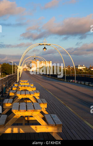 Southport Pier mit Blick auf die Stadt mit hölzernen Bänken beleuchtet mit der Abendsonne, Merseyside, UK Stockfoto