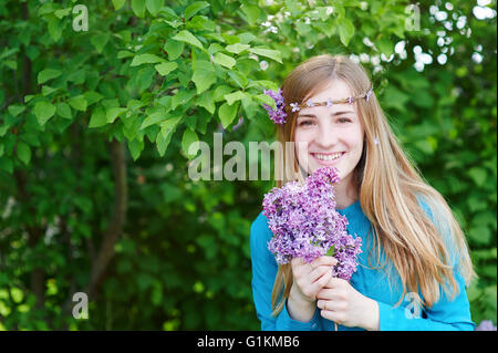 Schöne Frau mit Blumen Flieder in den Händen Stockfoto