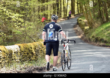 Übergewicht Radfahrer zu Fuß sein Fahrrad einen Hügel hinauf auf eine sportliche, Yorkshire Stockfoto