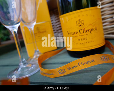 Veuve Clicquot Brut Luxus Champagner und Gläser auf Alfresco Garten Picknicktisch mit Picknickkorb hinter Stockfoto