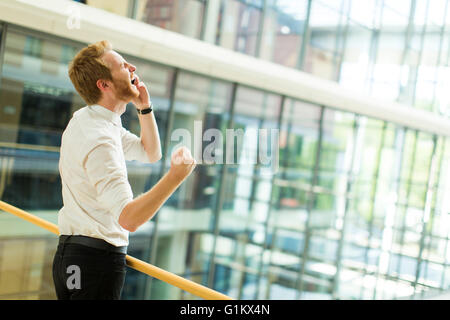 Aufgeregt Redhair junger Geschäftsmann reden über ein Handy im Büro Stockfoto