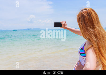 Glücklich attraktive Blondine im Bikini Fotografieren selbst an einem schönen sonnigen Strand Stockfoto