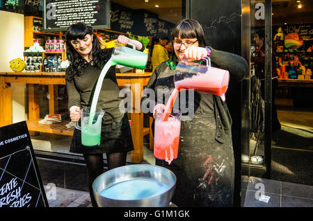 Zwei Mitarbeiterinnen und Mitarbeiter mischen Bad Kosmetik vor einem üppigen Geschäft. Stockfoto