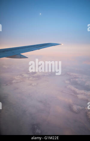 Blick auf rosa Nebel und Wolken über den Bergen bei Sonnenaufgang von einem Flugzeug mit dem Flügel in den Schuss. Stockfoto