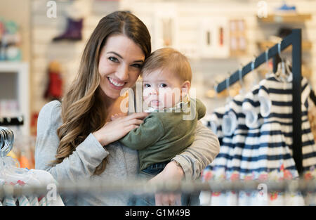 Kaukasische Mutter und Baby Sohn Einkaufen in Bekleidungsgeschäft Stockfoto