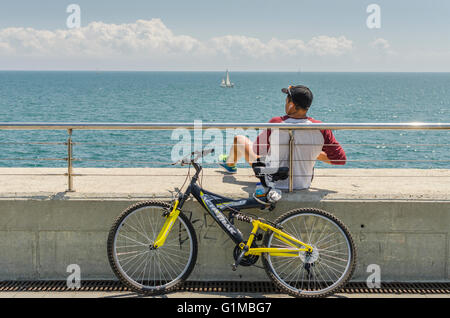 Sonntag Morgen. Ein Mann mit Ihrem Fahrrad entspannen mit Blick auf das Meer Stockfoto